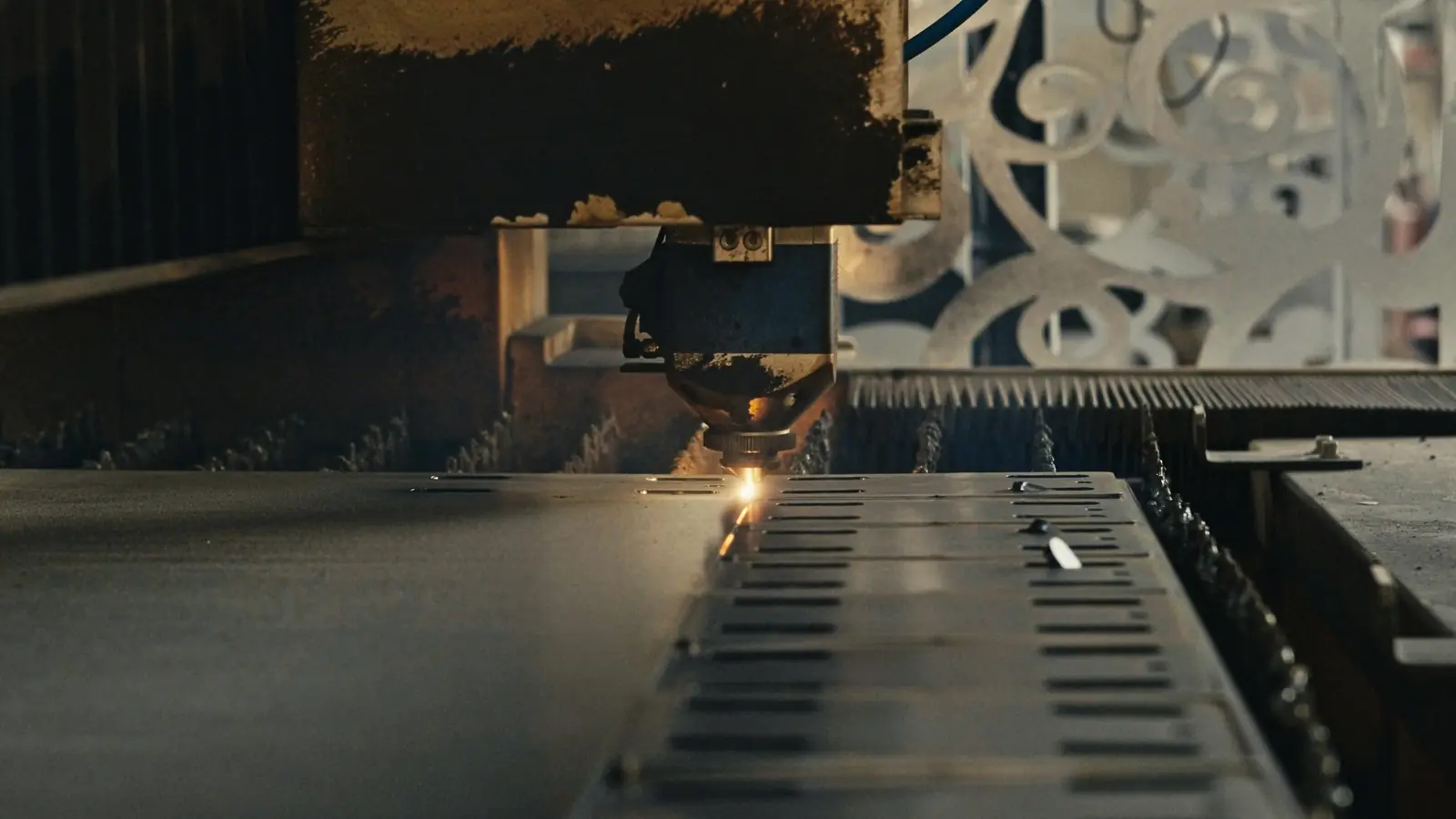 A laser cutting head works its way across a steel sheet.